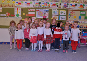 Dzieci z grupy II pozują do wspólnego zdjęcia. Dzieci są we większości przebrane w stroje w polskich kolorach narodowych.